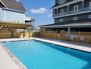 Una piscina con muelle de madera y zona vallada, rodeada de casas.