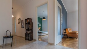 A spacious hallway with a marble floor, a bookshelf, a small table with a lamp, and a leather armchair. - Mole View by Wonderful Italy (Turin)
