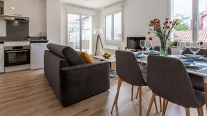 A modern kitchen with a built-in oven and a dining area with a table set for two. - Cap Océan by Interhome (Capbreton)