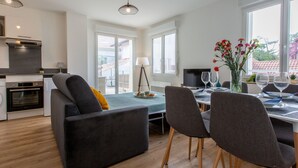 A modern kitchen with a built-in oven and a dining area with a table set for two. - Cap Océan by Interhome (Capbreton)
