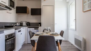 A compact kitchen with built-in appliances, a dining table with chairs, and a ceiling fan. - Cap Océan by Interhome (Capbreton)