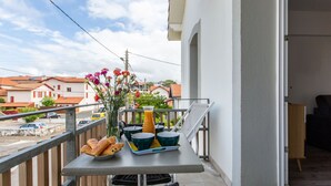 A balcony with a table set for breakfast, including croissants, a fruit bowl, and a vase of flowers. - Cap Océan by Interhome (Capbreton)