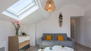 A modern living room with a skylight, grey sofa with yellow cushions, a wooden cabinet, and a small table with plants. - Cap Océan by Interhome (Capbreton)