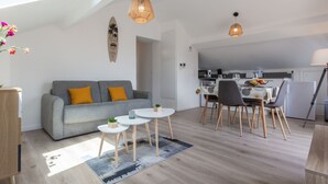 A modern apartment with a grey sofa, a dining table with chairs, a kitchen area, and a skylight. - Cap Océan by Interhome (Capbreton)