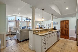 A spacious kitchen with a central island, white cabinetry, and a large window overlooking the balcony. - CSC4E High Roller by First Flight Rentals (Kill Devil Hills)
