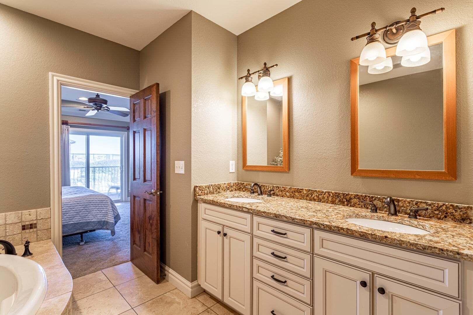 A bathroom with a double sink vanity, a large mirror, and a ceiling fan.