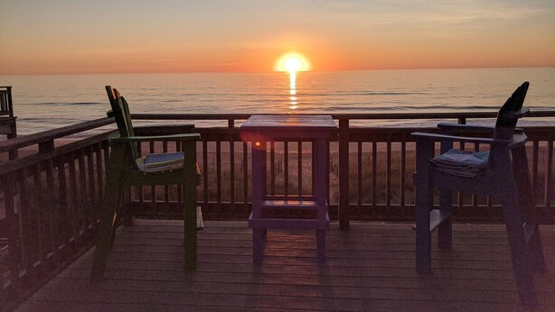 A wooden deck with two chairs facing a sunset over the ocean. - SS9 Raynorshine by First Flight Rentals (Kill Devil Hills)