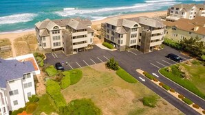 A coastal hotel with multiple buildings, a parking lot, and a view of the ocean. - SS9 Raynorshine by First Flight Rentals (Kill Devil Hills)