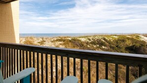 Eine Holzterrasse mit Blick auf Strand und Dünen.