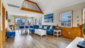Un salón amplio con un sofá azul, una mesa de centro blanca y una escalera de madera.
