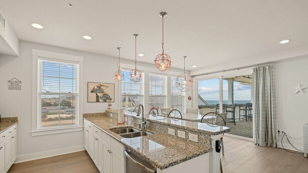 A modern kitchen with granite countertops, stainless steel appliances, and pendant lighting. - SC301- Langman's Sea Cabin by First Flight Rentals (Kill Devil Hills)