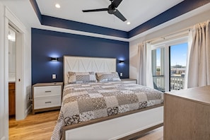 A bedroom with a bed, nightstands, a ceiling fan, and a window with curtains.