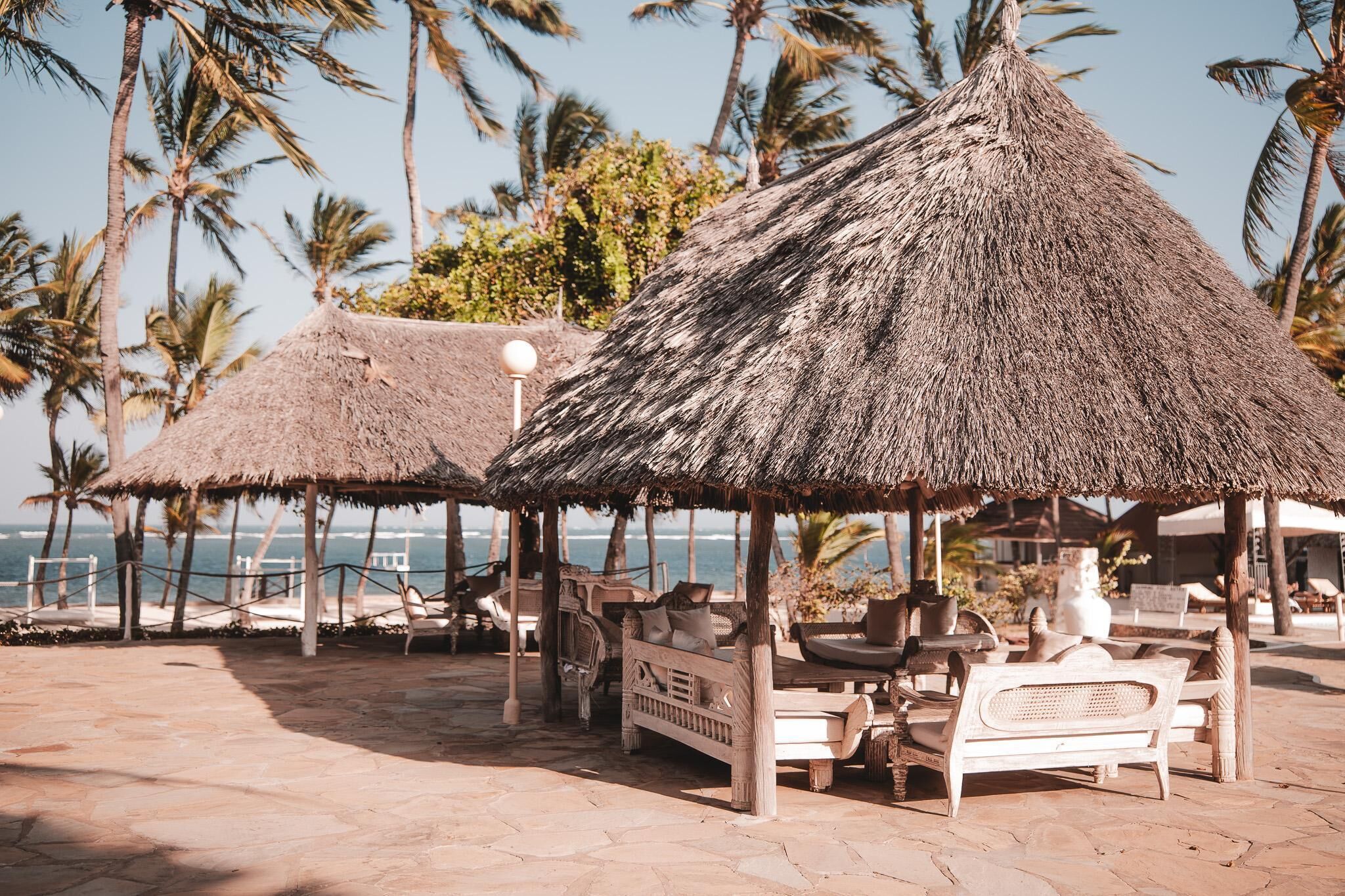 A beachside lounge area with thatched umbrellas and wicker furniture.