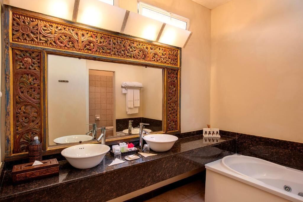 Un bagno con due lavandini, uno specchio grande e una vasca da bagno.