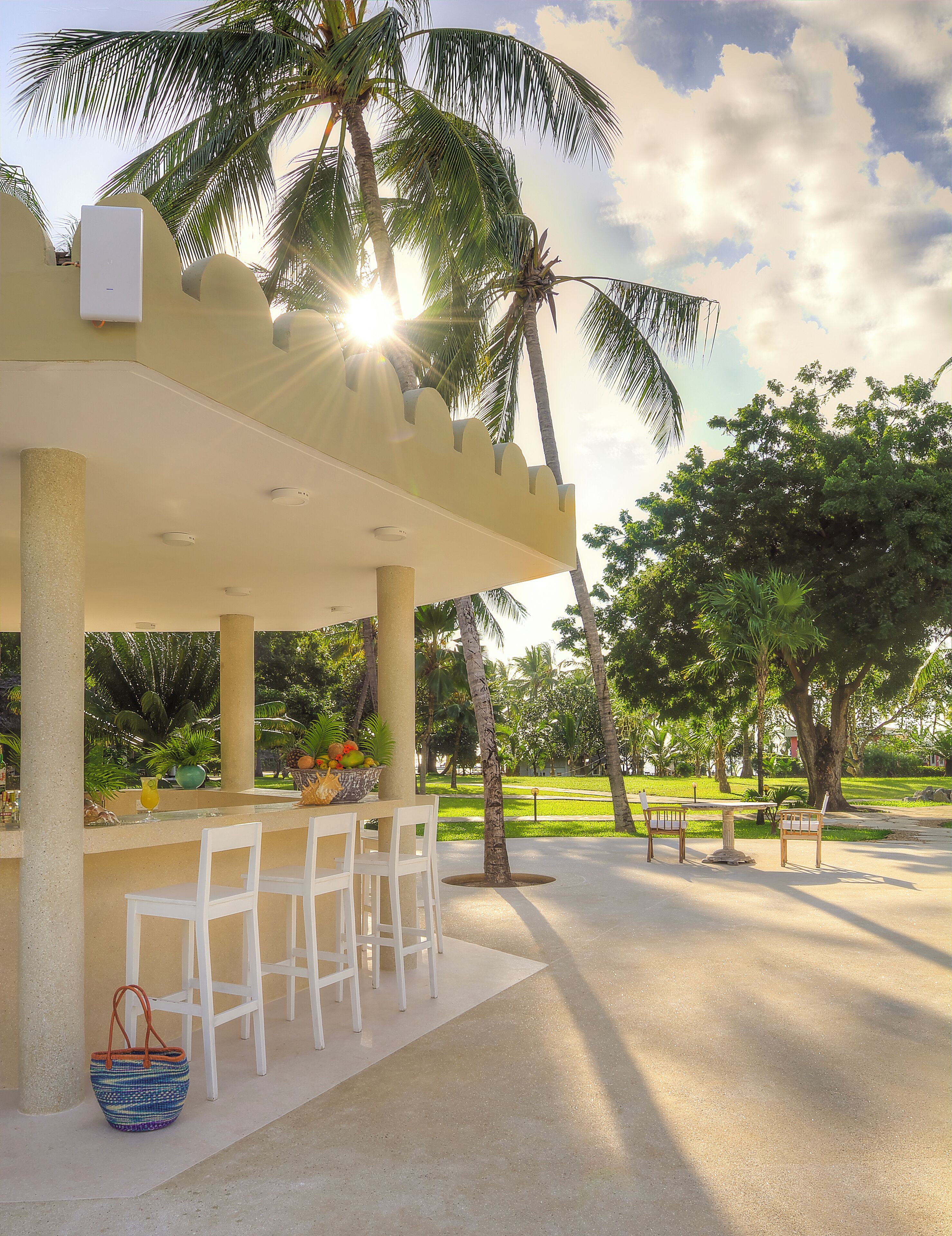 An outdoor patio area with a bar, white chairs, and a table.