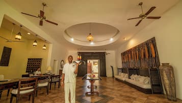 A spacious room with a dining area, a large bed, and a collection of paddles on the wall.