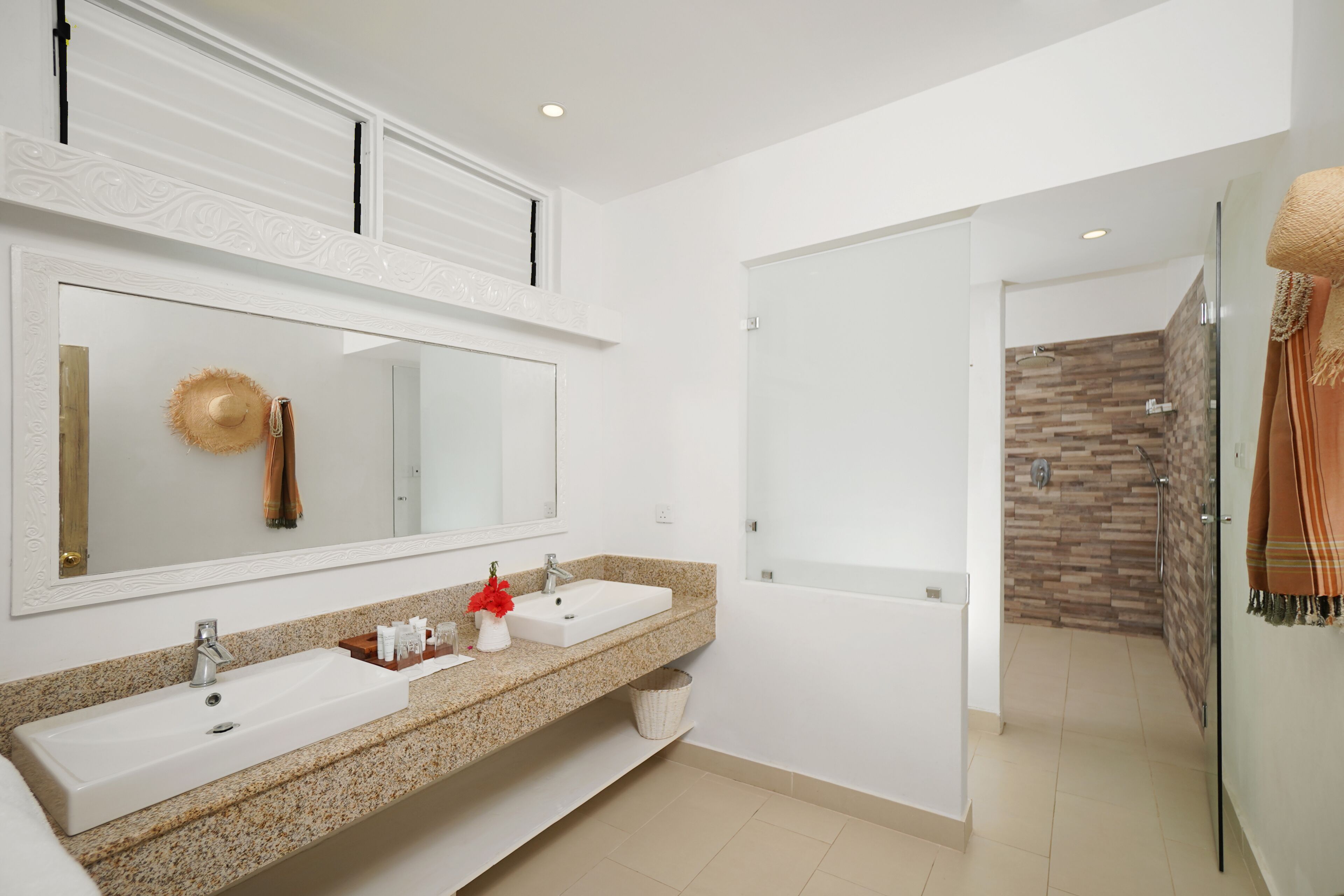 A modern bathroom with two sinks, a large mirror, and a shower area.
