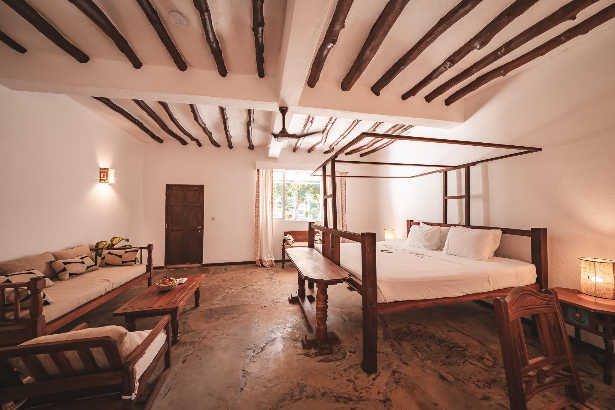 Una habitación rústica con cama con dosel, muebles de madera y suelo de piedra.