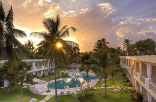 Un resort con piscina, palmeras y un edificio con balcones.