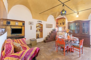 A dining area with a table set for four, surrounded by chairs, a television, and a cabinet. - Like A Dream in Sanremo (Sanremo)
