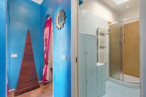 A bathroom with a shower, a vanity with drawers, a mirror, and a towel rack.