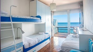 A room with bunk beds, a desk, a chair, a hanging lamp, and a view of the sea. - Sole Surf E Relax, Sea-view Balcony Apartment (Sanremo)