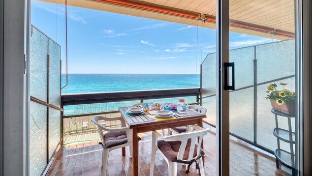 A balcony with a table set for dining, overlooking the sea. - Casa 3 Ponti With Sea-view Balcony and Parking (Sanremo)