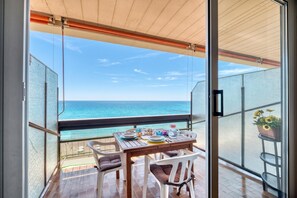 Ein Balkon mit Esstisch, mit Blick auf das Meer.
