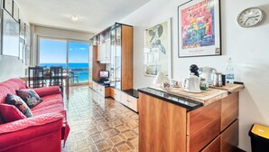 A modern kitchen with wooden cabinets, a red sofa, and artwork on the walls. - Casa 3 Ponti With Sea-view Balcony and Parking (Sanremo)