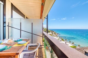 A balcony with a table set for dining, overlooking a coastal view. - Casa 3 Ponti (Sanremo)