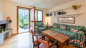 A living room with a sofa, a wooden table, a fireplace, and a bookshelf. - Plan Gorret Wonderful Apartment In Courmayeur (Courmayeur)