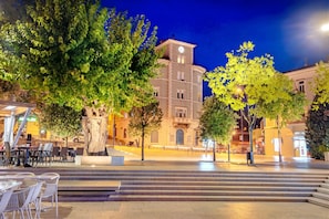 A public square with a building featuring a clock tower, surrounded by trees and outdoor seating. - Sea View Apartment Neti (Crikvenica)