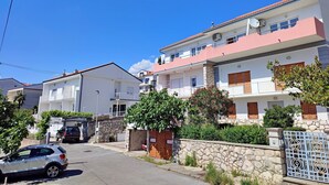 A residential building with a stone wall, a gated entrance, and a parked car. - Sea View Apartment Neti (Crikvenica)