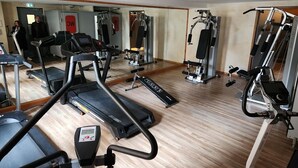 A gym with treadmills, weight machines, and a mirrored wall.