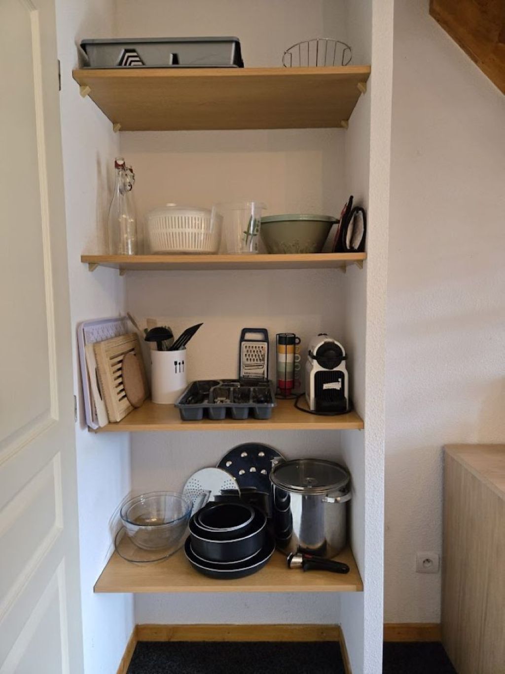 A kitchen with wooden shelves holding various kitchen items.
