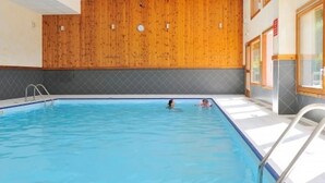An indoor swimming pool with wooden paneling on the walls and a tiled floor.