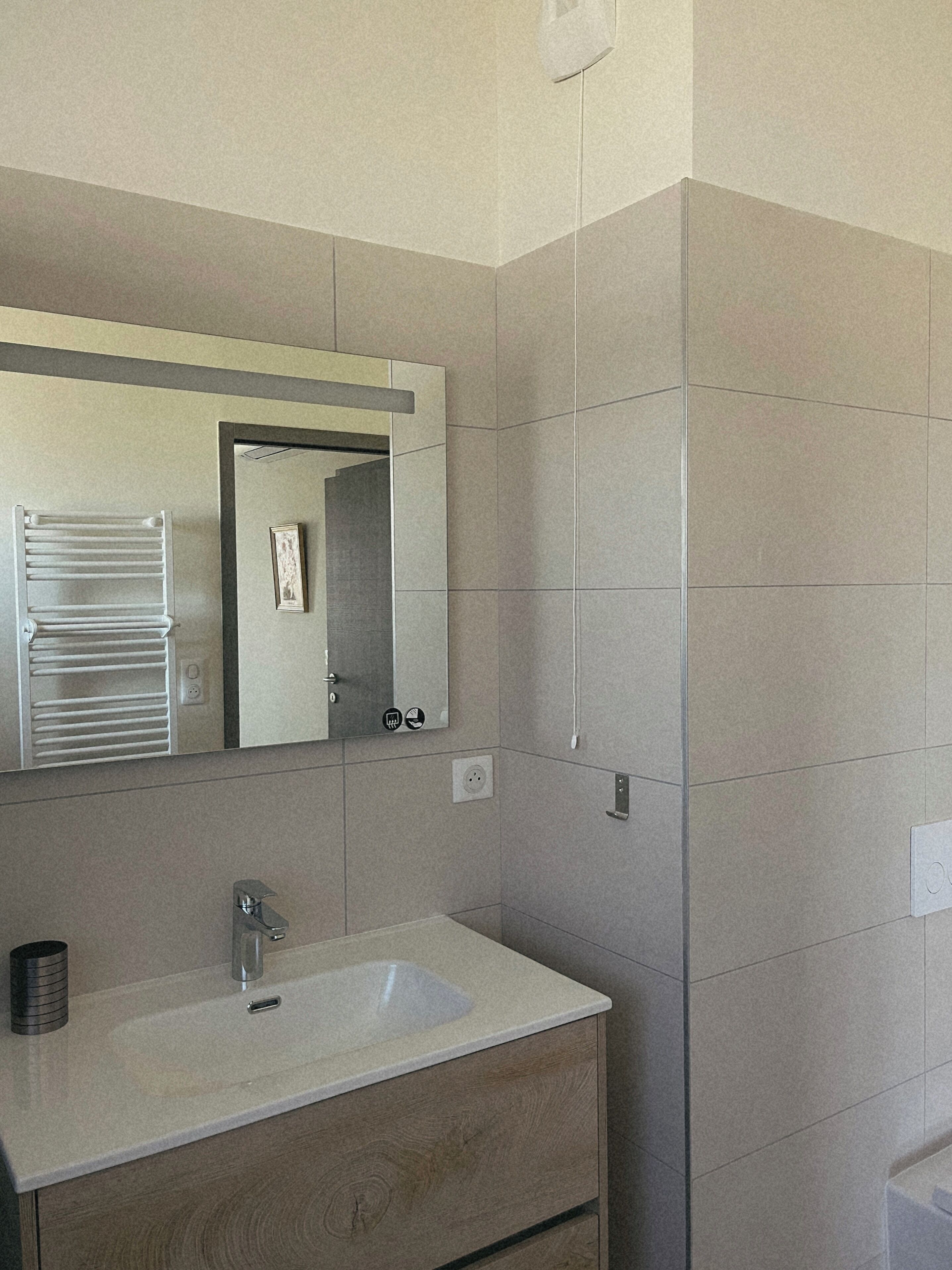 Un bagno con un lavandino bianco, uno specchio e un porta asciugamani.