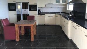 Une cuisine moderne avec un coin repas, comprenant une table et des chaises en bois, un four encastré et un plan de travail noir.