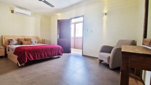 Une chambre à coucher comprenant un lit, des tables de chevet, une chaise et une porte donnant sur l’extérieur.
