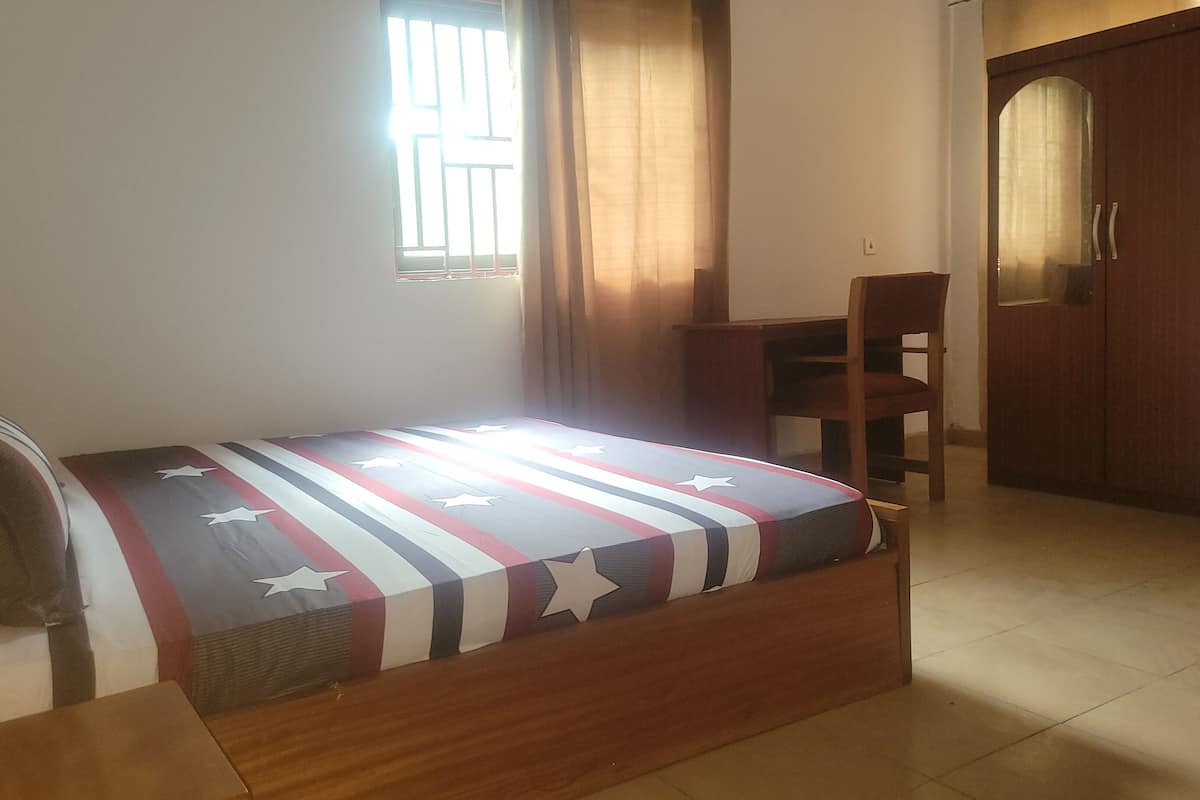 Ein Schlafzimmer mit einem Bett, einem Schreibtisch, einem Stuhl und einem Kleiderschrank.