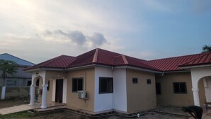 A two-story house with a red roof and beige walls. - Assembly Hotel - Esiama  (Esiama)