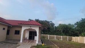 A building with a red roof and a covered entrance. - Assembly Hotel - Esiama  (Esiama)