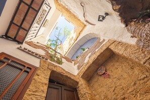 Une cour avec une porte en bois, une fenêtre à carreaux et un mur orné de carreaux décoratifs.