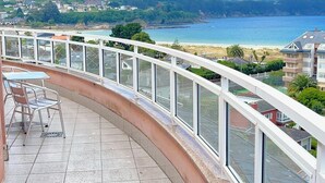 Un balcon avec vue sur une plage et des collines.