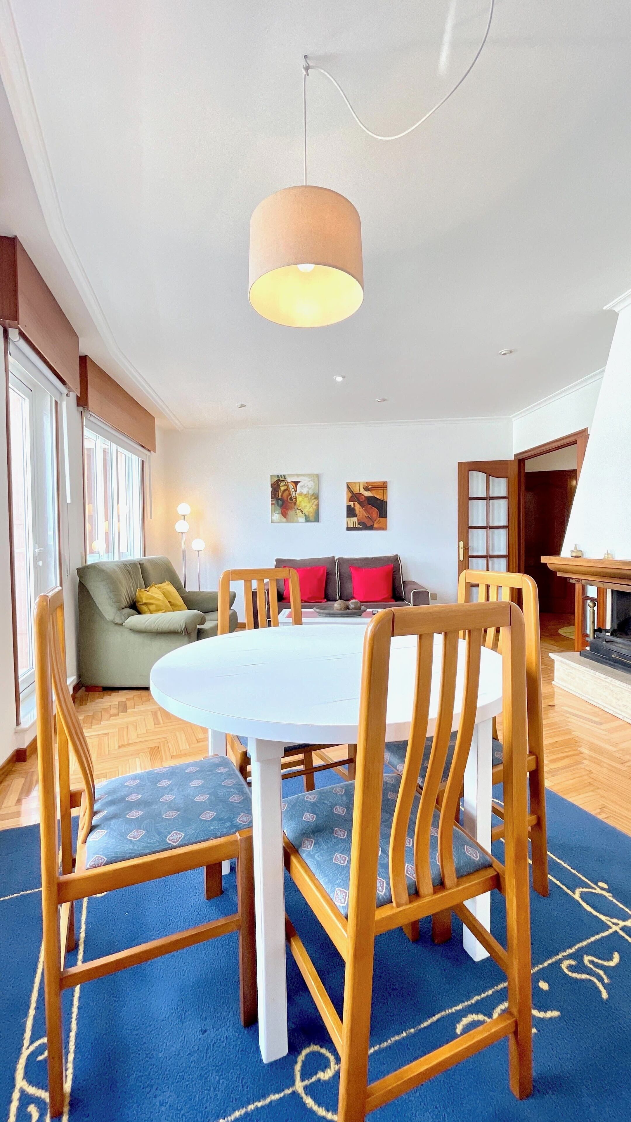 A dining area with a round table, wooden chairs, and a blue carpet.