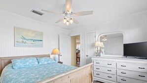 A bedroom with a wooden bed, white dresser, TV, and ceiling fan. - Awesome & Affordable 3 Bdrm, 2 Ba with easy beach access, and Gulf & Bay Views.  (Gulf Shores)