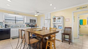 A kitchen with a wooden table and chairs, white cabinets, and a ceiling fan. - Awesome & Affordable 3 Bdrm, 2 Ba with easy beach access, and Gulf & Bay Views.  (Gulf Shores)