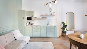 Une cuisine moderne avec des meubles de couleur vert clair, un plan de travail blanc et un luminaire suspendu.
