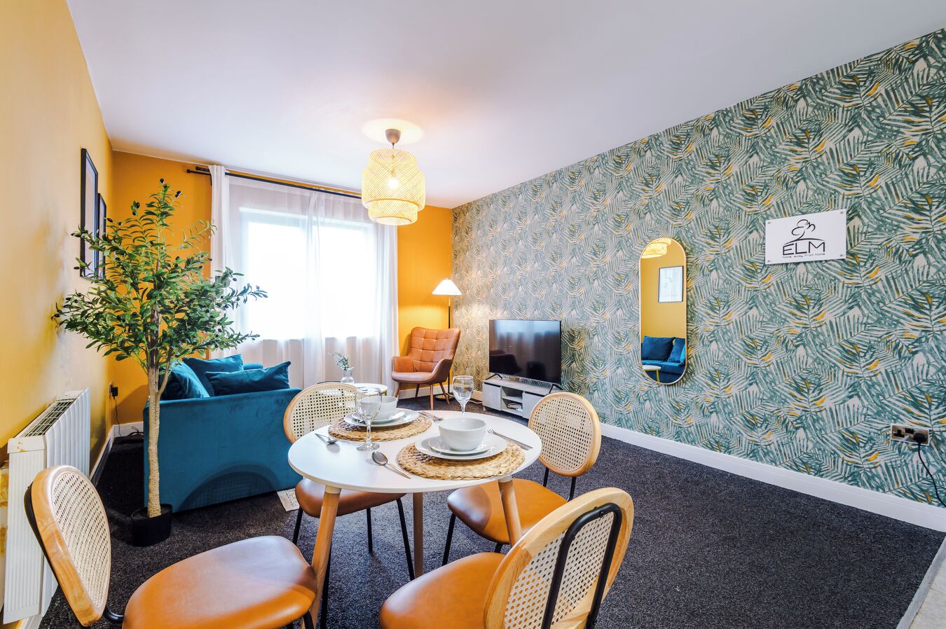 A compact living space with a dining area, a sofa, a TV, and a mirror.