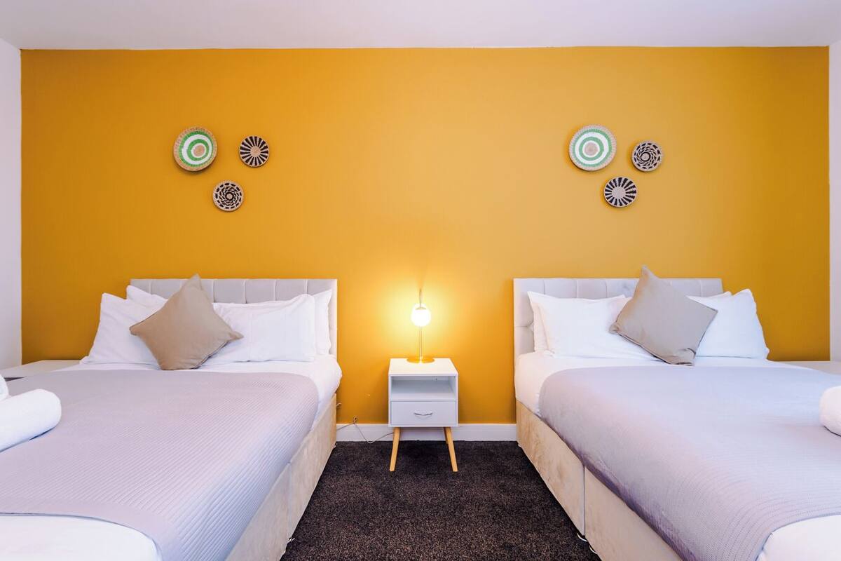 Une chambre d’hôtel avec deux lits, une table de chevet et des œuvres d’art décoratives au mur.